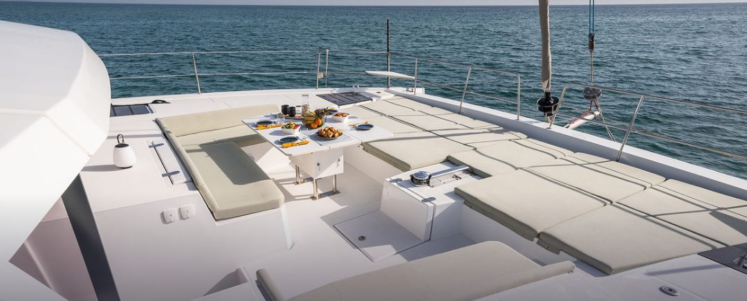The catamaran's foredeck with brunch laid out, looking out over the water